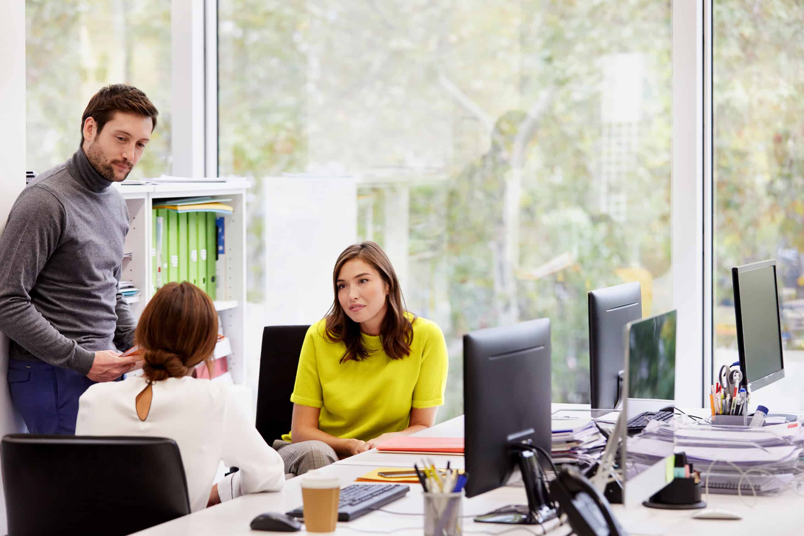 three people in office setting talking with each other