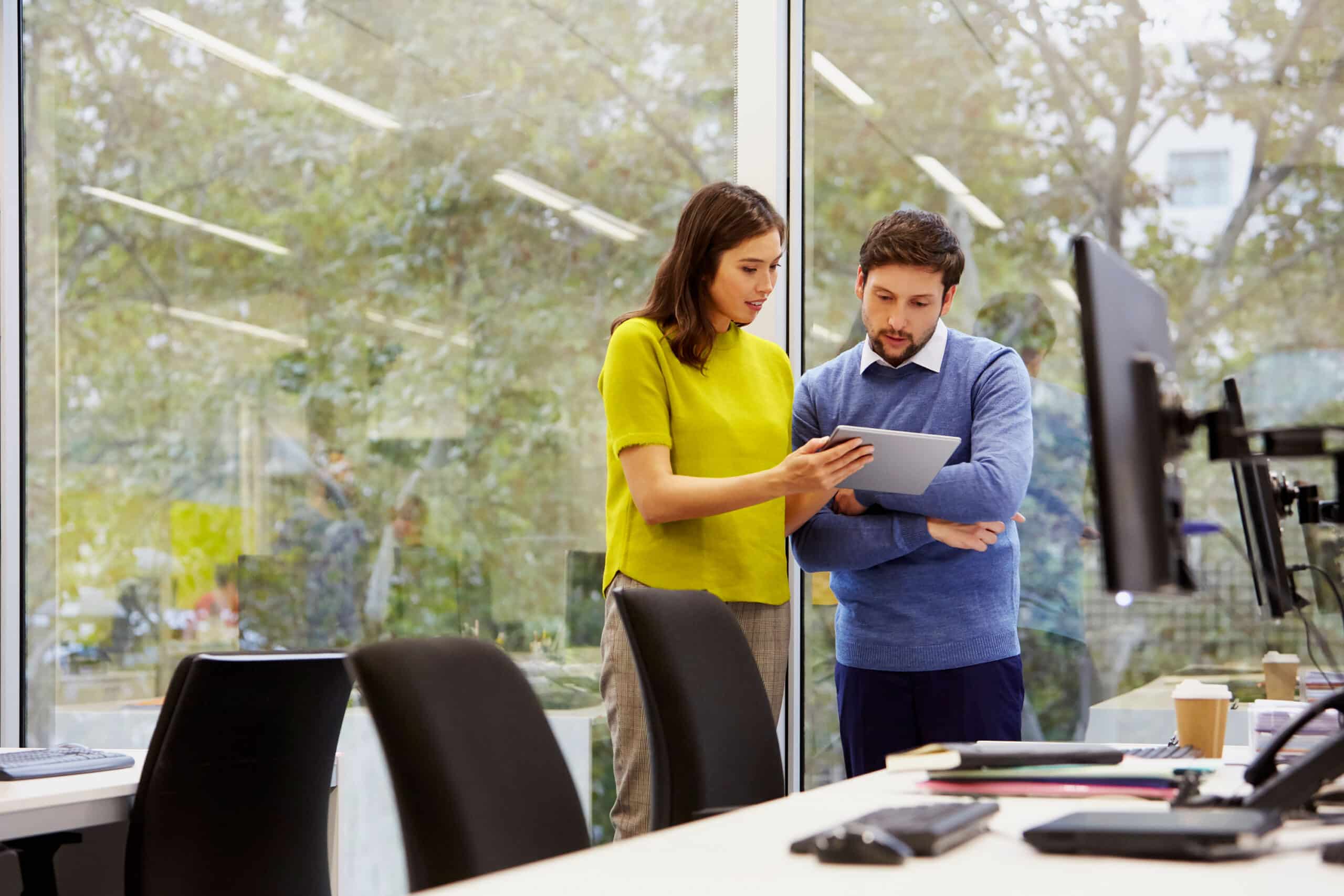 Two people in office setting looking at tablet