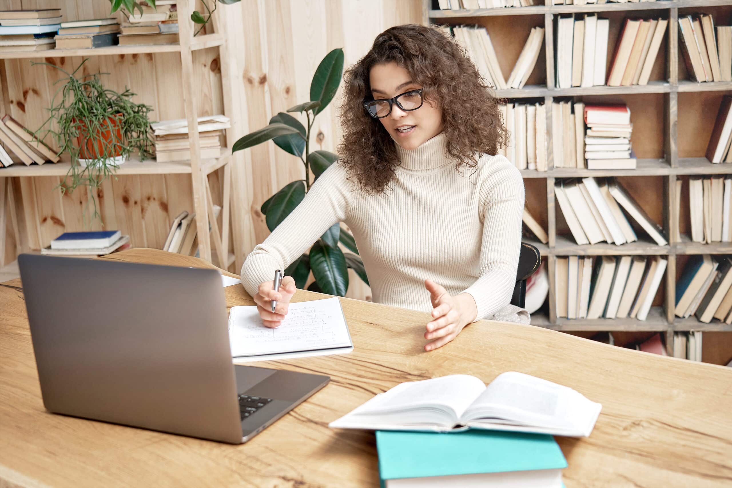 Person in front of laptop and notebook with pen in hand