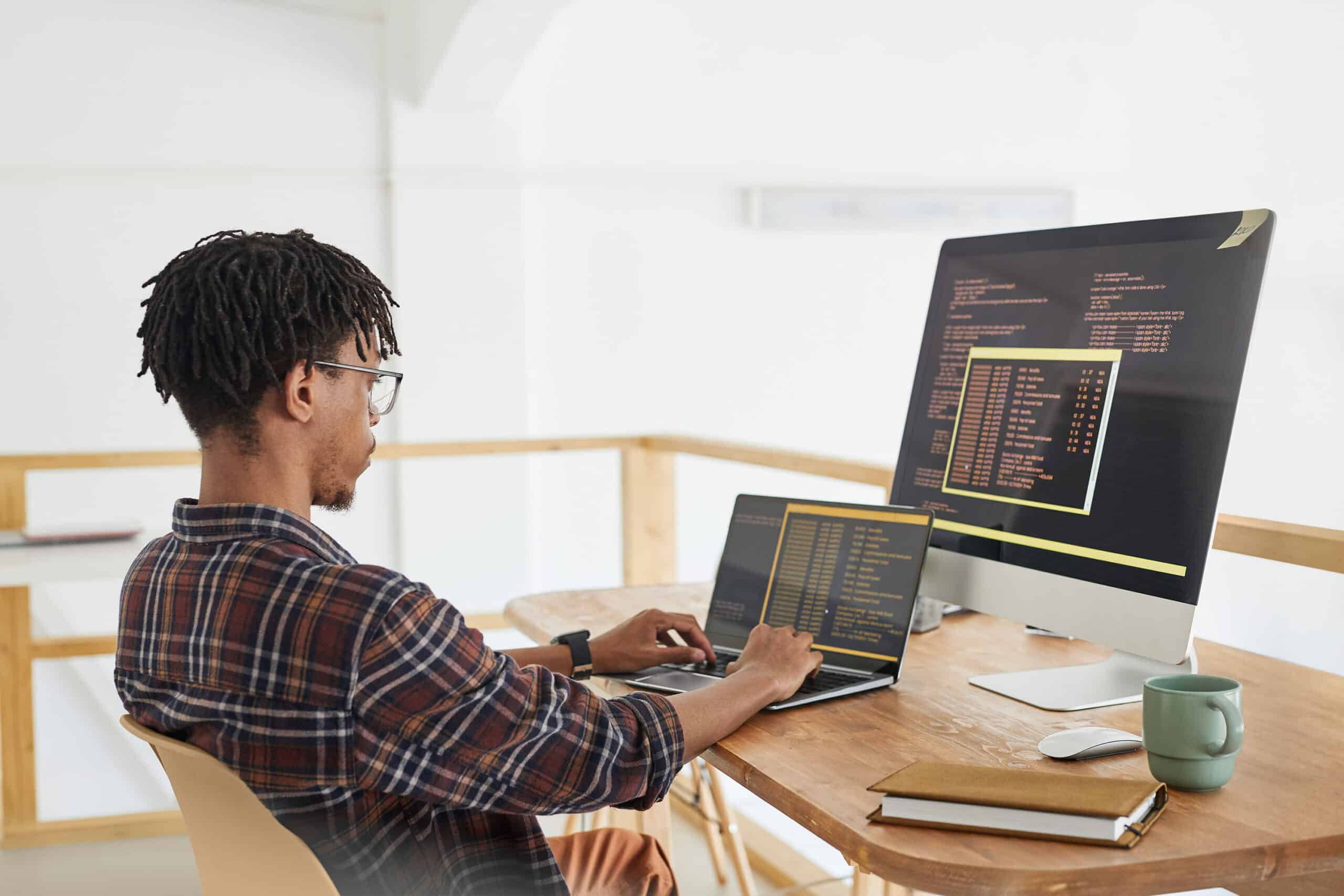 Person in front of two computer screens with code