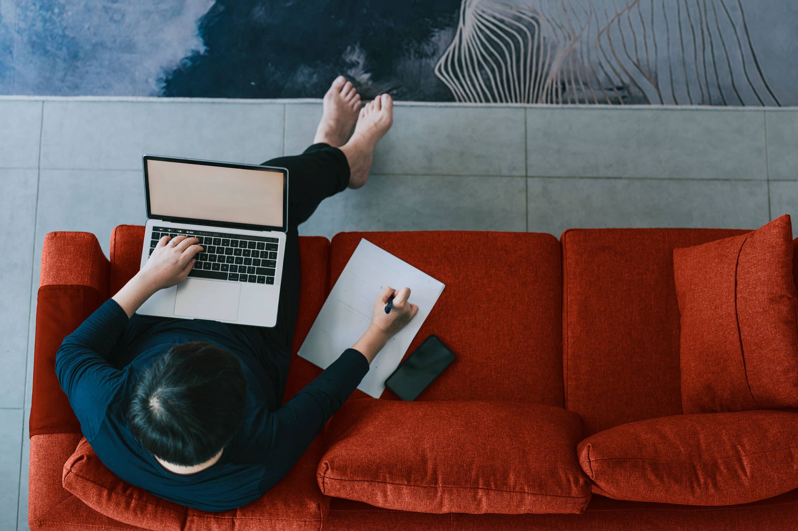 Person on couch with laptop and notebook